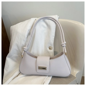 Close-up of cream underarm bag with a gold rectangular metal clasp and knot strap detail