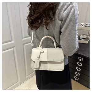 Détail d'un sac à bandoulière crème chic avec mélange de cuir lisse et de textures tissées