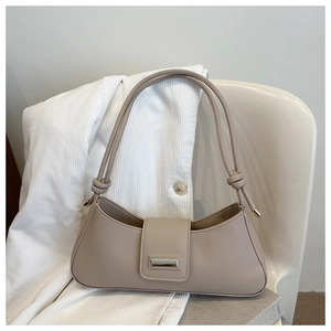 Detailed view of the knotted shoulder strap and elegant metal hardware on a cream hobo bag