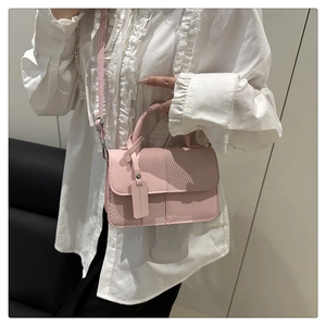 Dettaglio della borsa rosa con trama intrecciata e targhetta decorativa alla moda