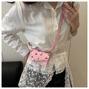 Pink shoulder bag with red cherry prints and golden metal bar on the front flap