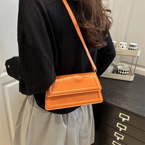 Orange leather crossbody square bag shown on model with smooth texture and sleek flap