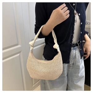 Detail of woven crescent shoulder bag with white knotted strap and straw texture