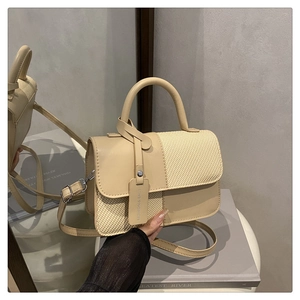 Détail du sac bandoulière beige en cuir et tissage avec boucles en métal et étiquette