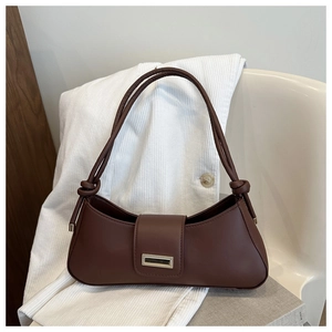 Detailed close-up of dark brown baguette bag with metal buckle on velvet texture