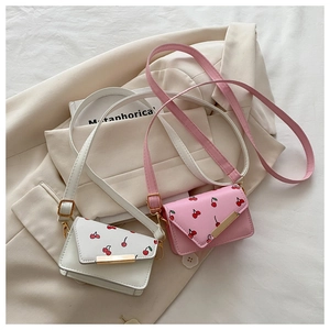 Detailed view of cherry print crossbody bags in white and pink with gold metal trim