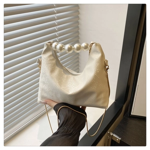 Detail of white snake texture leather handbag with large pearl handle and gold chain strap