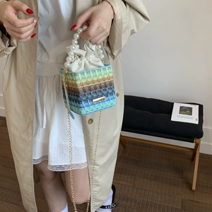 Handcrafted woven bucket bag with gradient stripes, pearl handle, and gold chain strap