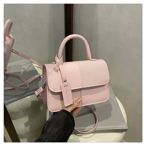 Détail du sac bandoulière patchwork rose avec cuir lisse, texture tissée et poignée
