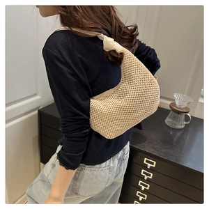 Detail of hand-knotted shoulder strap and beige woven texture on hobo straw bag