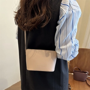 Minimalist beige leather crossbody bucket bag with adjustable strap and brand logo