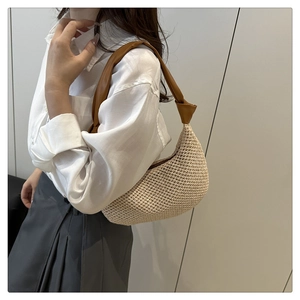 Detail of hand-woven straw hobo bag with a knotted brown leather shoulder strap on a model
