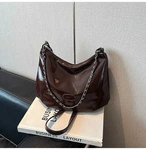 Deep brown glossy patent leather tote bag with silver chain strap and oval detail