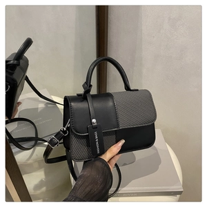 Dettaglio della borsa a tracolla minimalista in pelle nera e tessuto grigio spinato