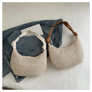 Detail of woven straw shoulder bags with leather straps in white and brown colors