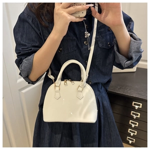 White shell-shaped handbag with adjustable strap shown on model in a casual setting