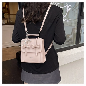 Detail of a light pink mini backpack with sweet bow accents and a pearl pendant charm