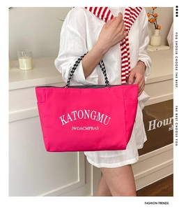 Detail of hot pink water-resistant tote bag with letter print and woven handles