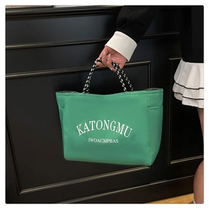 Detail view of the bright green tote bag featuring black and white braided rope handles