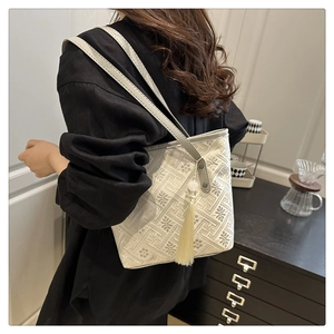 Detail shot of chic beige tote bag with grey retro geometric patterns and tassel detail