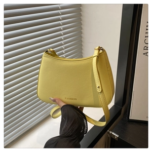 Détail du sac sous l'aisselle jaune clair avec boucle dorée et texte du logo mode