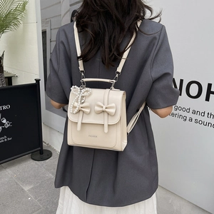 Chic beige bow backpack for women with pearl charm shown in a street style setting