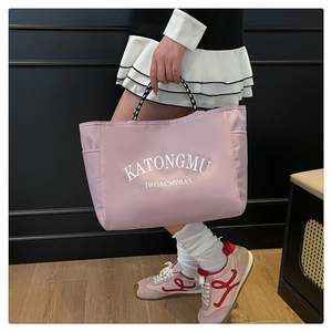 Detailed view of pink nylon tote bag featuring woven handles and side pocket storage