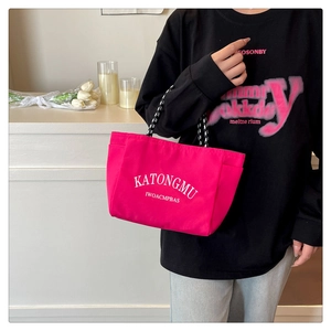 Pink nylon tote bag detail with white KATONGMU lettering and woven rope handles