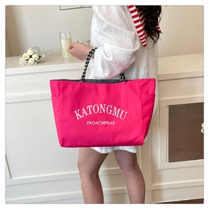 Detail of fuchsia tote bag with letter print and checkered woven handle on a white dress