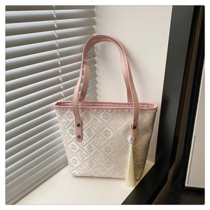 Macro detail of Chinese style embroidery tote with leather handle and white tassel
