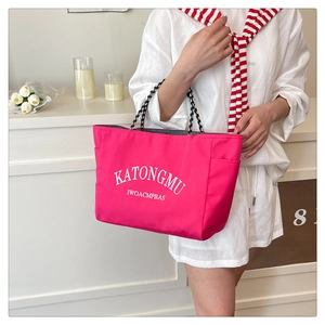 Close-up of pink tote bag with white lettering and checkered handles for fashion styling