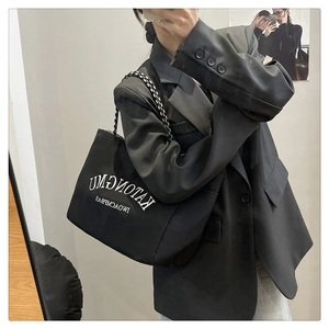 Detail of black tote bag with white lettering and woven check cord handles