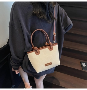 Détail d'un sac seau tressé contrasté avec poignées en cuir marron et boucles dorées