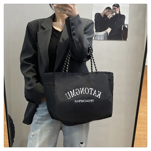 Close-up of black water-resistant tote bag with white lettering and side pocket