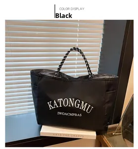 Detail of black nylon tote bag with white KATONGMU print and woven handle on window sill
