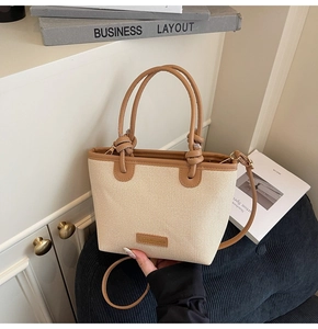 Détail du sac cabas en paille tressée avec bordure en cuir marron et anse nouée