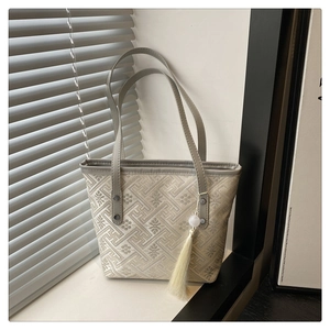 Detail of grey jacquard tote bag featuring traditional floral patterns and white silk tassel