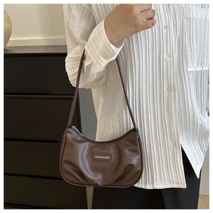 Detail of dark brown PU leather hobo bag with pleated texture and fashion metal plaque