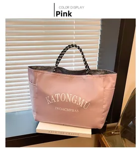 Pink nylon tote bag detail with KATONGMU lettering and black and white rope handles