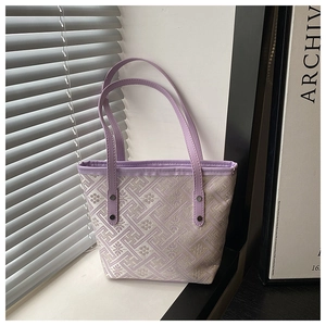 Macro shot of purple leather trim and silver rivets on the patterned tote handbag