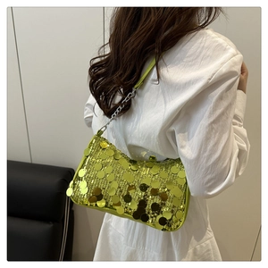Lime green sequin shoulder bag with metal chain strap shown on a model in white