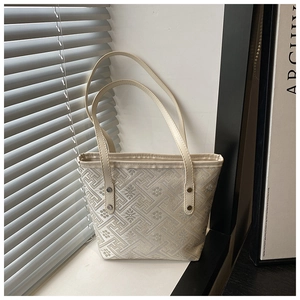 Close-up of textured floral jacquard fabric and rivet details on the cream tote bag