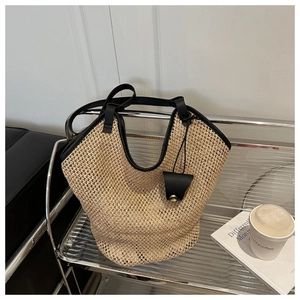 Close-up of woven straw tote bag with black leather trim and small pouch on metal shelf