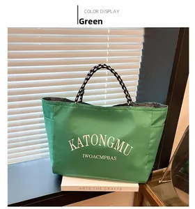 Close-up of green large capacity tote bag with woven stripe handles and letter print