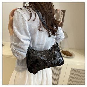 Gros plan d'un sac hobo à paillettes noires avec chaîne argentée porté par le mannequin