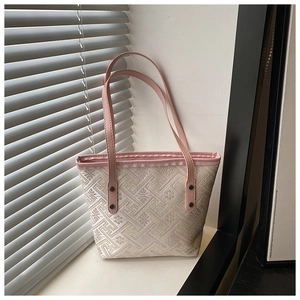 Detailed close-up of woven pink plaid texture and leather handles on a tote bag