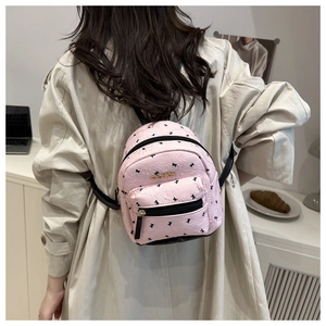 Pink mini backpack detail featuring golden fashion tag and chic black ribbon patterns