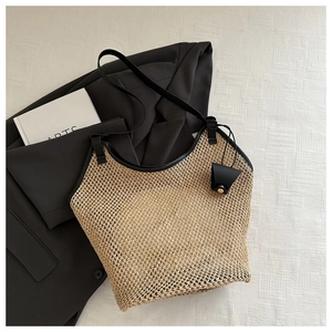 Dettaglio borsa tote in paglia con finiture in pelle nera e tracolla lunga