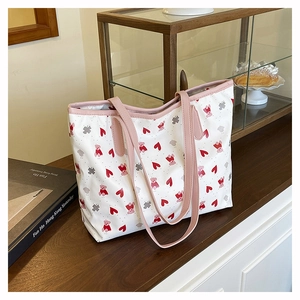 Detailed view of white bear print tote bag on a wooden table with pink leather straps