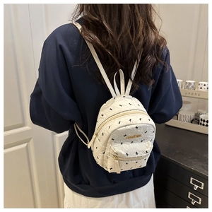 Detail view of mini white backpack with bird patterns and golden fashion metal plate